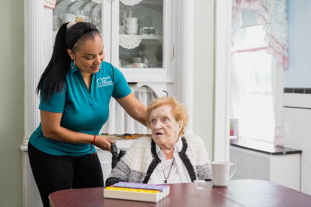 Caregiver pushing client up to the table in her wheelchair. Caregiver pushing client up to the table in her wheelchair.
