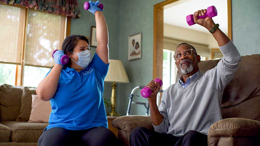 Caregiving and senior exercising while sitting down