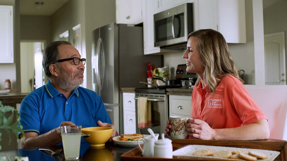 Caregiver serving meal to senior