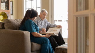 male client and caregiver sitting looking through a book